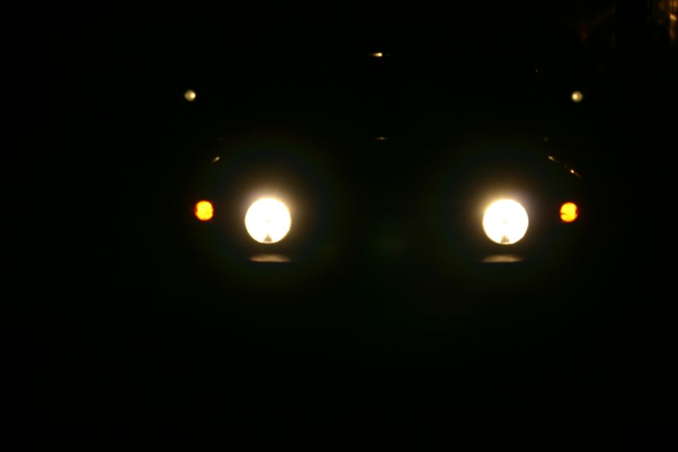 Front view of vehicle headlights and amber turn signals at night
