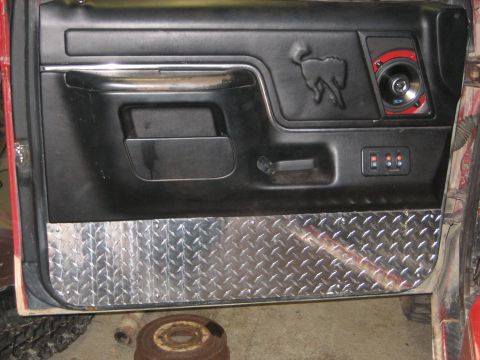1990 Ford Bronco - Interior door panel with a horse emblem and diamond plate accent.