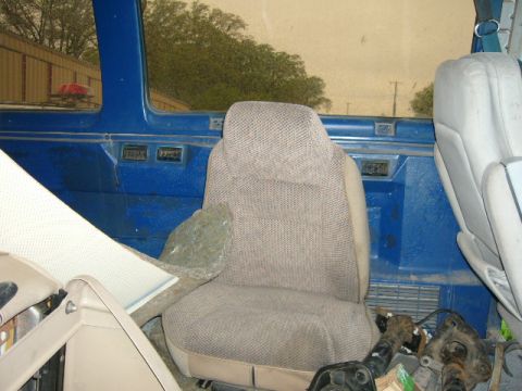 1978 Ford E250 - Interior view of a van with two seats and blue paneling, showing some disassembled parts on the floor.