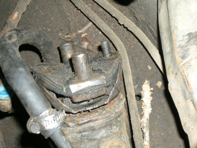 Close-up of a worn steering box mount with a hose clamp and rubber hose