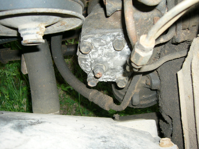 Steering box with hoses and bolts. Part of a vehicle's engine bay