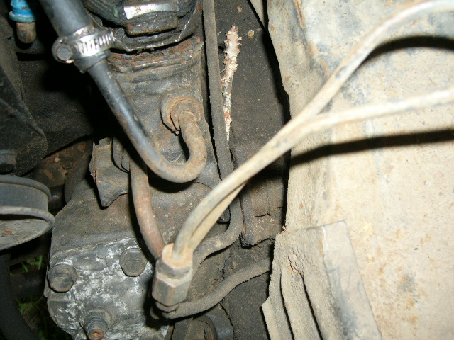 Close-up of a vehicle's steering box with metal hoses attached