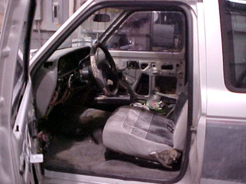 1990 Ford Bronco II - The interior of a Ford Ranger is shown with the driver's side door open and parts removed.