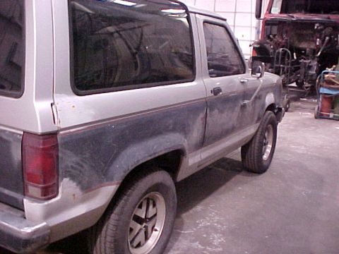 1990 Ford Bronco II - A 1990 Ford Bronco II in a workshop, showing its two-tone paint scheme and side profile.