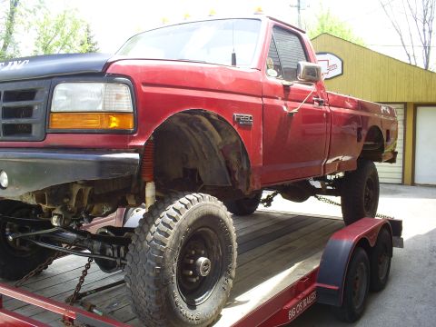 1994 Ford F-250 - This lifted red pickup truck, identified as an F-250 by its badge, appears to be from the early to mid-1990s.
