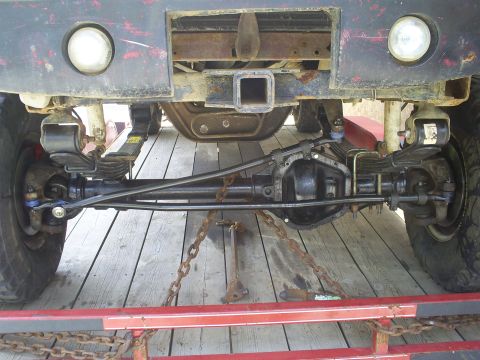 1994 Ford F-250 - Undercarriage view of a truck's rear axle, suspension, and hitch receiver, secured with chains on a trailer.