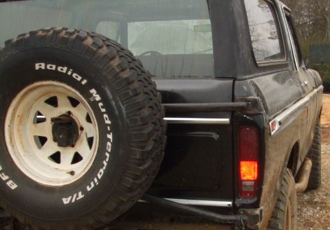 1979 Ford Bronco - The rear of a black Ford Bronco is shown, a spare tire and a partial view of the taillight.