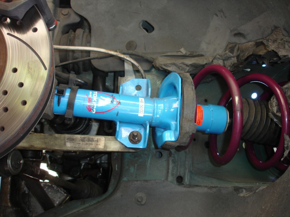 Blue Tokico shock absorber with red coilover spring and vented brake rotor