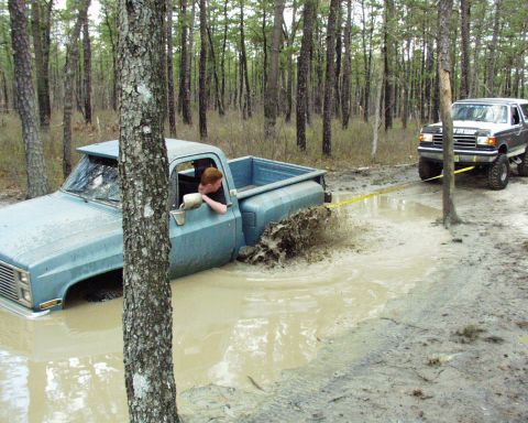 1989 Ford Bronco - A 1989 Ford Bronco pulls a light blue pickup truck from a muddy clearing in a forest.