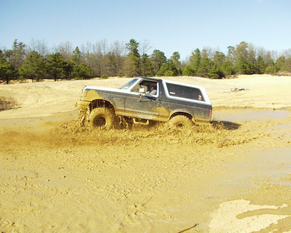 1989 Ford Bronco driving through mud, 3q-front view