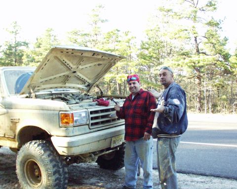1989 Ford Bronco - Two men stand next to a 1989 Ford Bronco with its hood open, possibly working on the engine.