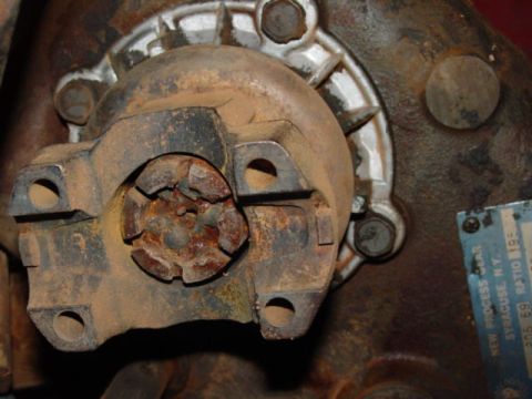 1986 Ford Bronco - Close-up of a rusty driveshaft U-joint and transfer case flange with a partial label visible.