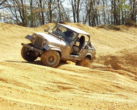 1989 Ford Bronco - Off-roading in a Jeep CJ-7 on a sandy, hilly terrain.