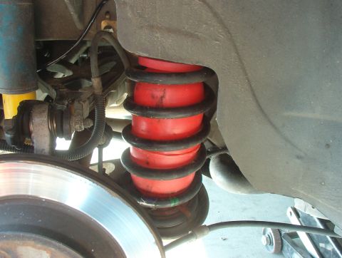 1993 Ford Bronco - Close-up view of a vehicle's rear suspension system, including air springs and a shock absorber.