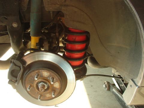 1993 Ford Bronco - Close-up view of a vehicle's rear suspension system, red air springs and a yellow shock absorber, with a Supermotors.net watermark.