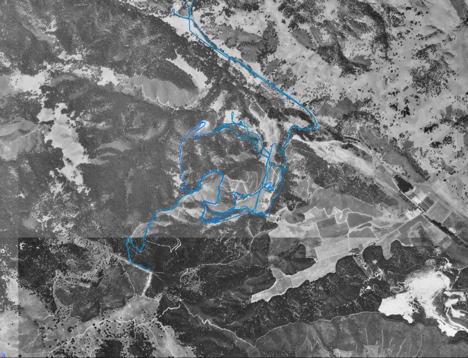 Black and white aerial map with a blue route line traced over hilly terrain