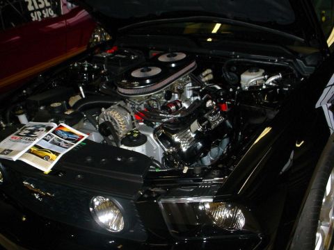1972 Ford Ranchero - Engine bay of a black car with chrome details and magazines on the side.