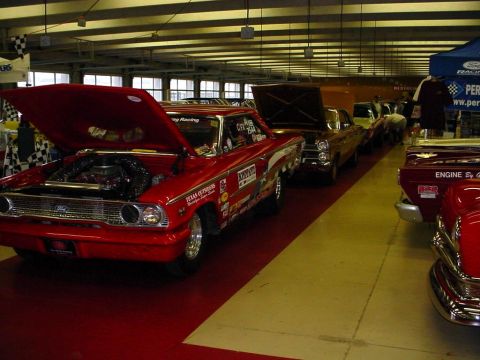 1972 Ford Ranchero - A red 1964 Ford sedan, likely a Fairlane or Galaxie, is displayed with its hood open, revealing the engine and covered in racing decals.