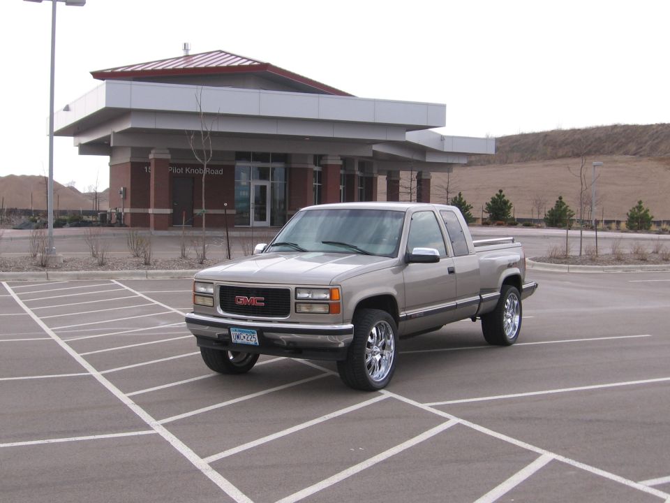 Tan GMC extended-cab pickup truck with chrome wheels in a parking lot