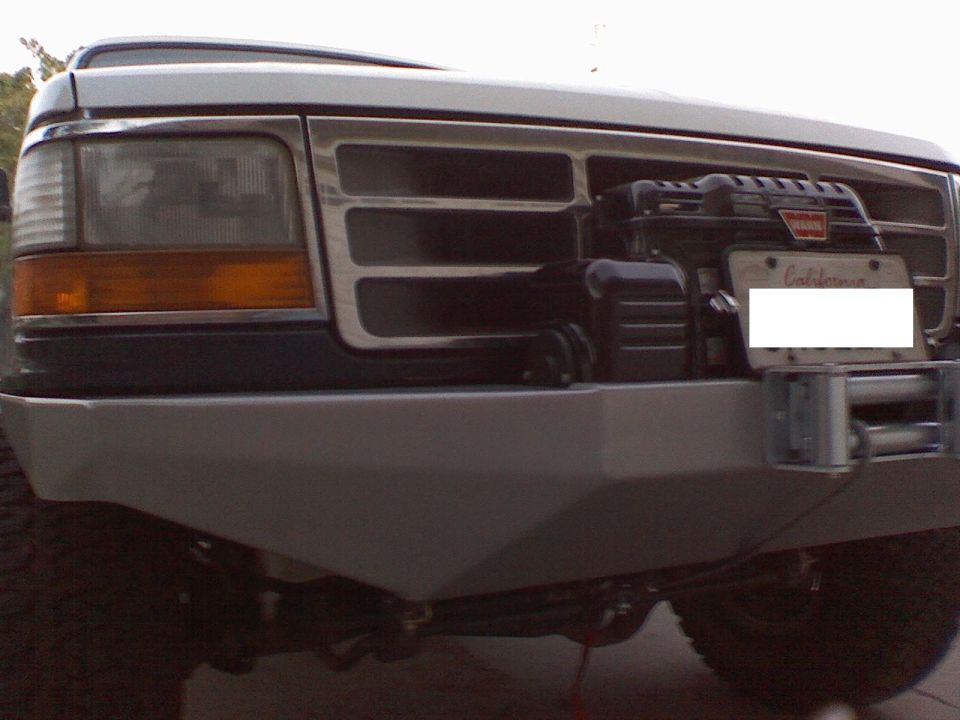 Truck front grille close-up with winch mounted on bumper and covered license plate