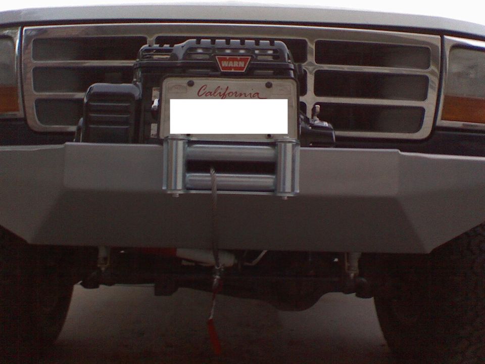 Front of a Ford truck with a WARN winch mounted on the aftermarket bumper. California license plate is visible
