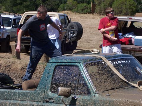1991 Ford Bronco - A muddy green pickup truck is the focus, with 'Bronco' visible on the windshield, during an off-road event.