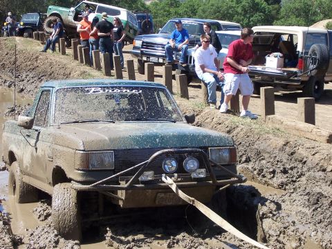 1991 Ford Bronco - A green 1991 Ford Bronco is stuck in a muddy ditch during an off-road event.