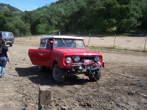1991 Ford Bronco - A red off-road vehicle is parked on a dirt track with its door open, a tow rope attached to the front.