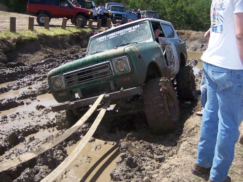 1991 Ford Bronco - Off-road vehicles navigate a muddy course during an event.