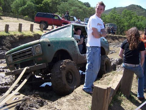 1991 Ford Bronco - A green off-road vehicle navigates a muddy obstacle course during an event.