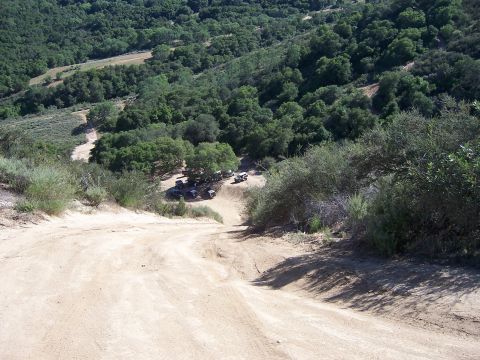 1991 Ford Bronco - Several SUVs are gathered off a dirt road in a wooded area.