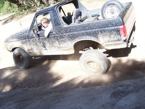 1991 Ford Bronco - A driver navigates a muddy trail in a black 1991 Ford Bronco during an off-road event.