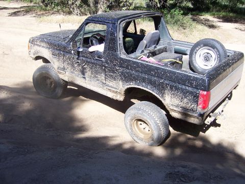1991 Ford Bronco - Muddy Bronco navigating a dirt path during an off-road event.