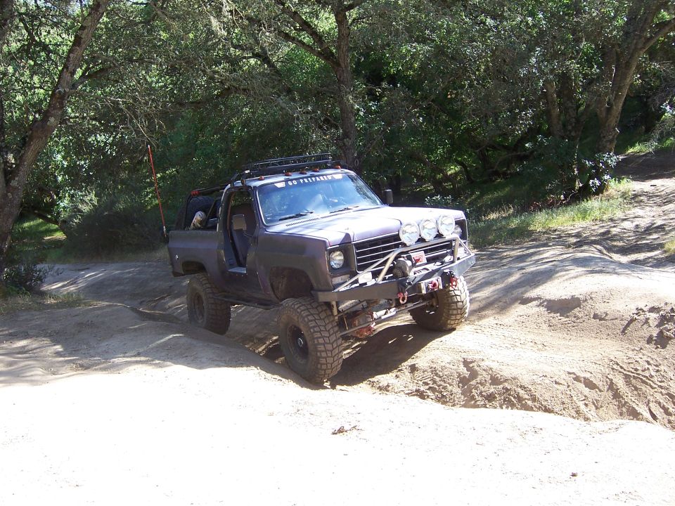Dark off-road truck with winch and auxiliary lights on a dirt trail