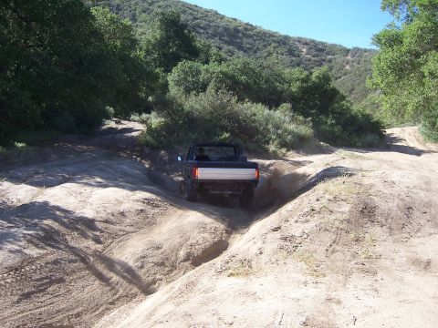 1991 Ford Bronco - Ford Bronco navigates a challenging off-road trail during a sunny day event.