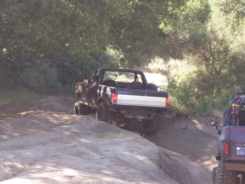 1991 Ford Bronco - A black Ford Bronco navigates an off-road trail with another vehicle visible to the right.