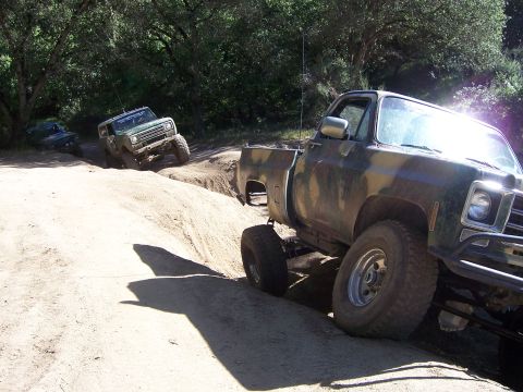 1991 Ford Bronco - Several off-road vehicles navigate a challenging dirt track during an event.