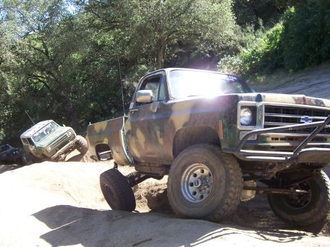 1991 Ford Bronco - Multiple off-road vehicles navigate a steep dirt trail during an outdoor event.