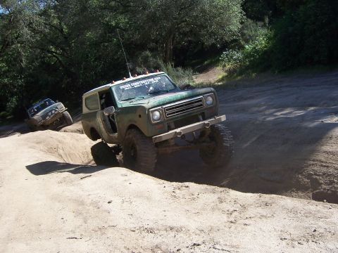 1991 Ford Bronco - Two off-road vehicles navigate a challenging dirt path on a sunny day.