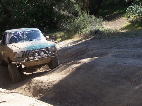 1991 Ford Bronco - A Ford Bronco navigates a challenging off-road trail on a sunny day.