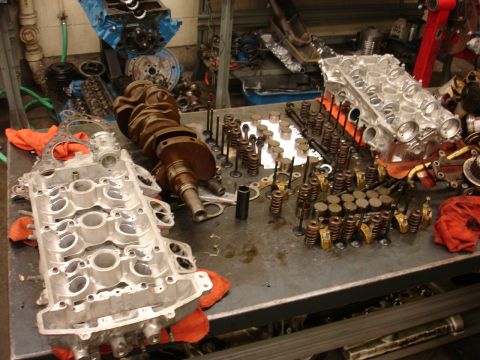 1992 Ford Taurus - Disassembled engine components, including a crankshaft and cylinder heads, are organized on a metal workbench.
