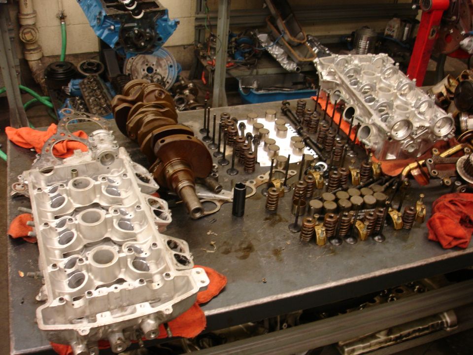 Engine block, crankshaft, and valves laid out on a workbench