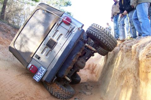 2004 Jeep Wrangler - A Jeep Wrangler is stuck in a deep ditch, with onlookers observing the precarious situation.
