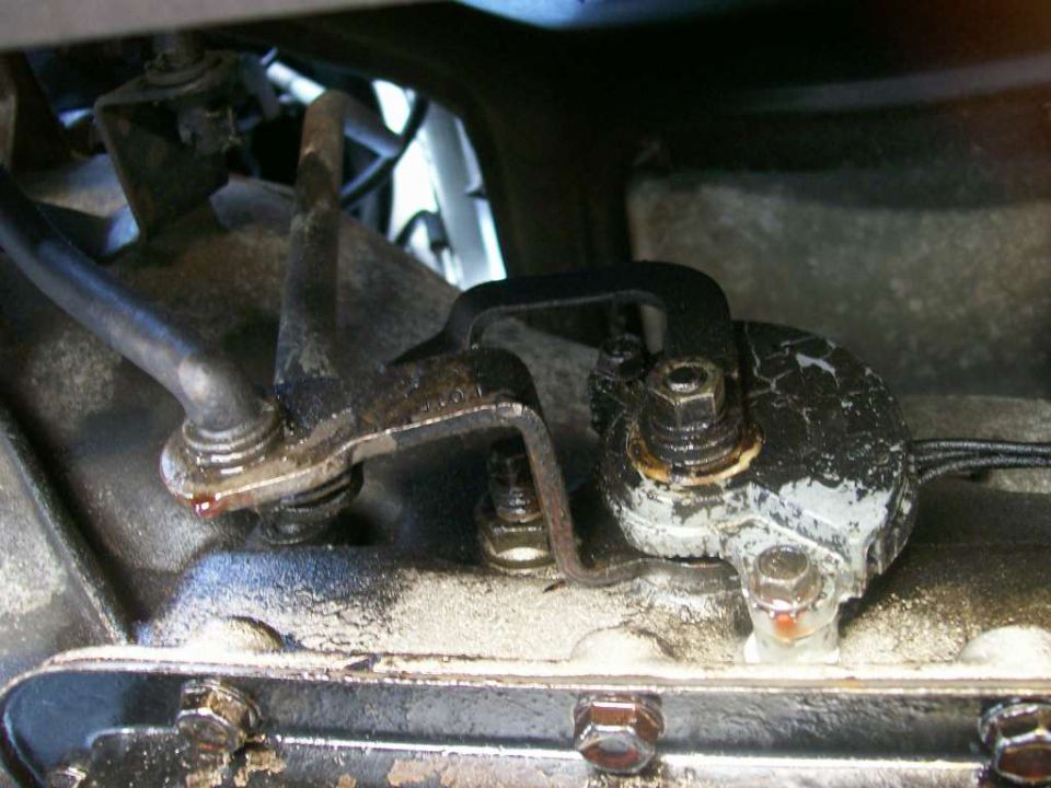 Close-up of a vehicle's transmission linkage with some fluid leakage