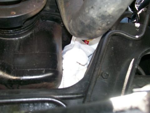 1984 Ford Bronco - Close-up view of an engine oil filter and oil pan, with a white cloth placed beneath.