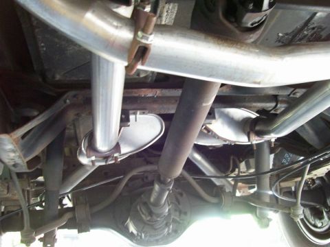 1984 Ford Bronco - Undercarriage view of a vehicle's exhaust system and drivetrain components.