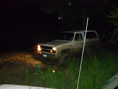 1992 Ford Bronco - A dirty SUV is seen driving off-road at night, with its headlights illuminating the path ahead.