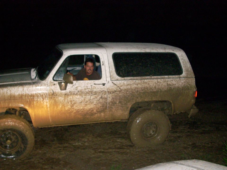 Mud-covered white SUV side view, driver visible