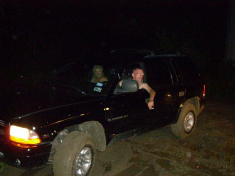 1992 Ford Bronco - Two people are in a black SUV at night, with mud on its tires.