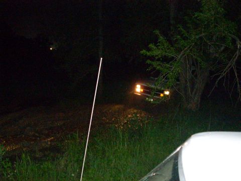 1992 Ford Bronco - A 1992 Ford Bronco is seen parked on a grassy bank at night, with its headlights illuminated.